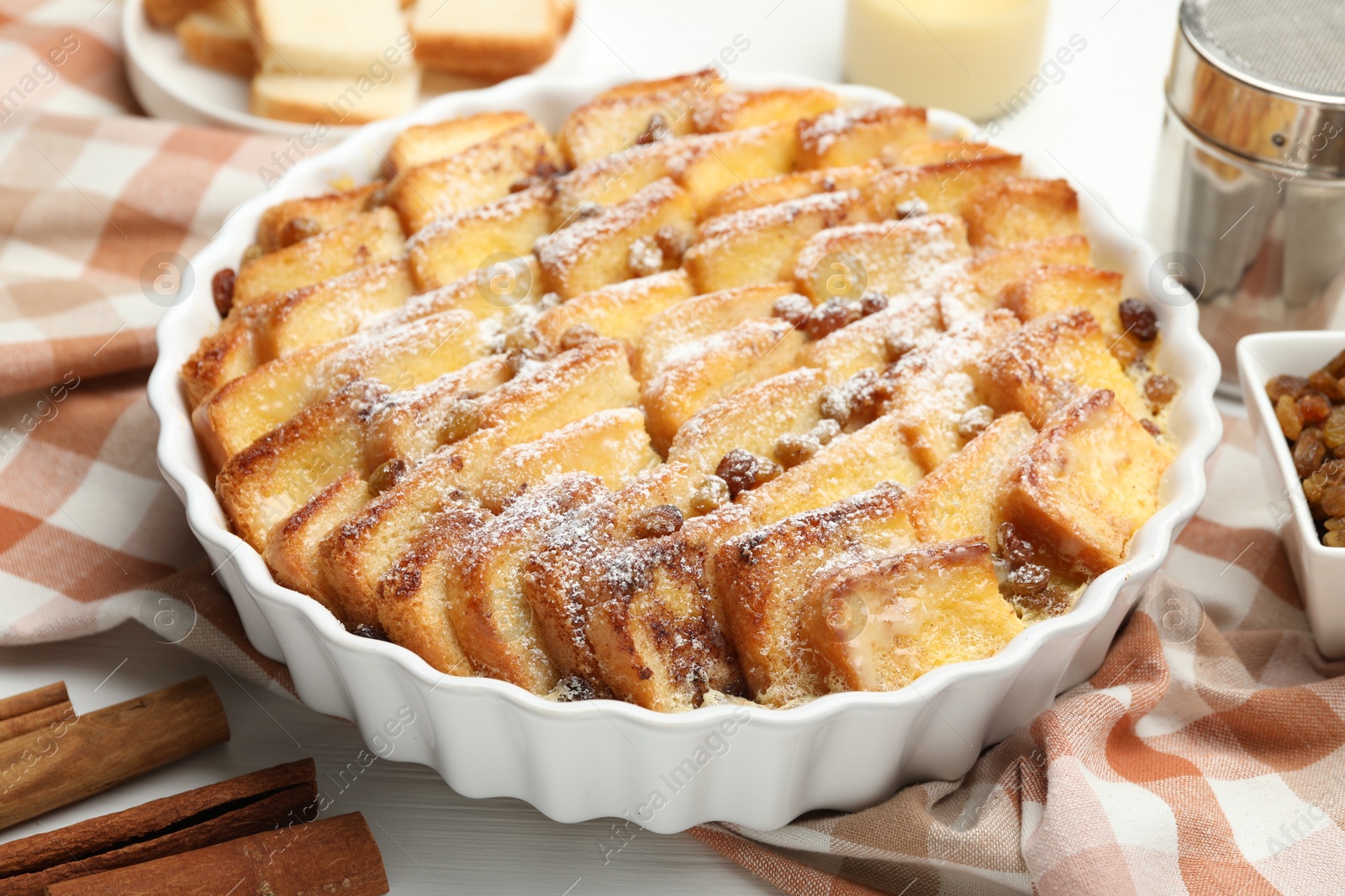 Photo of Delicious bread pudding with raisins and powdered sugar on table, closeup