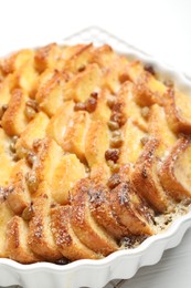 Photo of Delicious bread pudding with raisins on white table, closeup