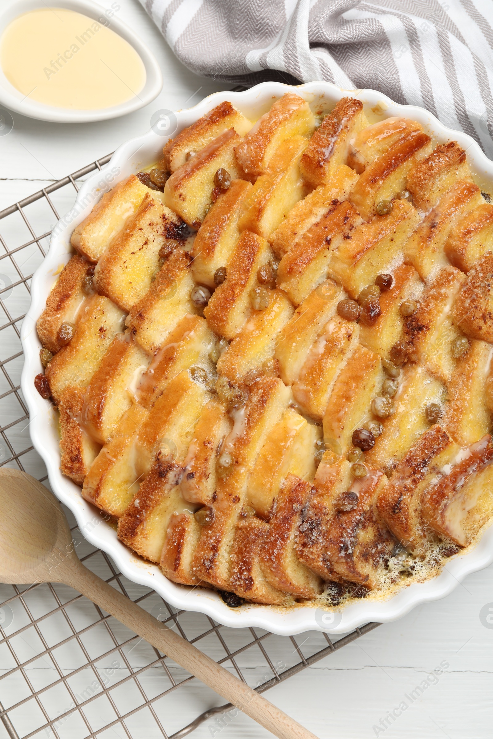 Photo of Delicious bread pudding with raisins and condensed milk on white table, flat lay