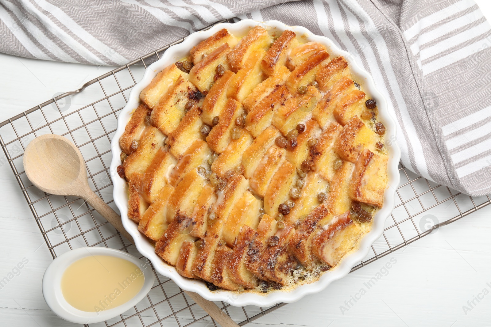 Photo of Delicious bread pudding with raisins and condensed milk on white table, flat lay