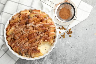 Photo of Delicious bread pudding with raisins and cinnamon on grey table, flat lay. Space for text