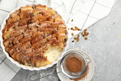 Photo of Delicious bread pudding with raisins and cinnamon on grey table, flat lay. Space for text