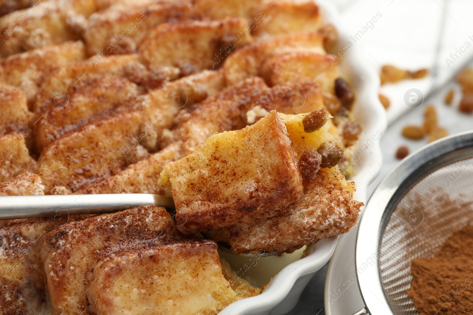 Photo of Eating delicious bread pudding with cinnamon at table, closeup