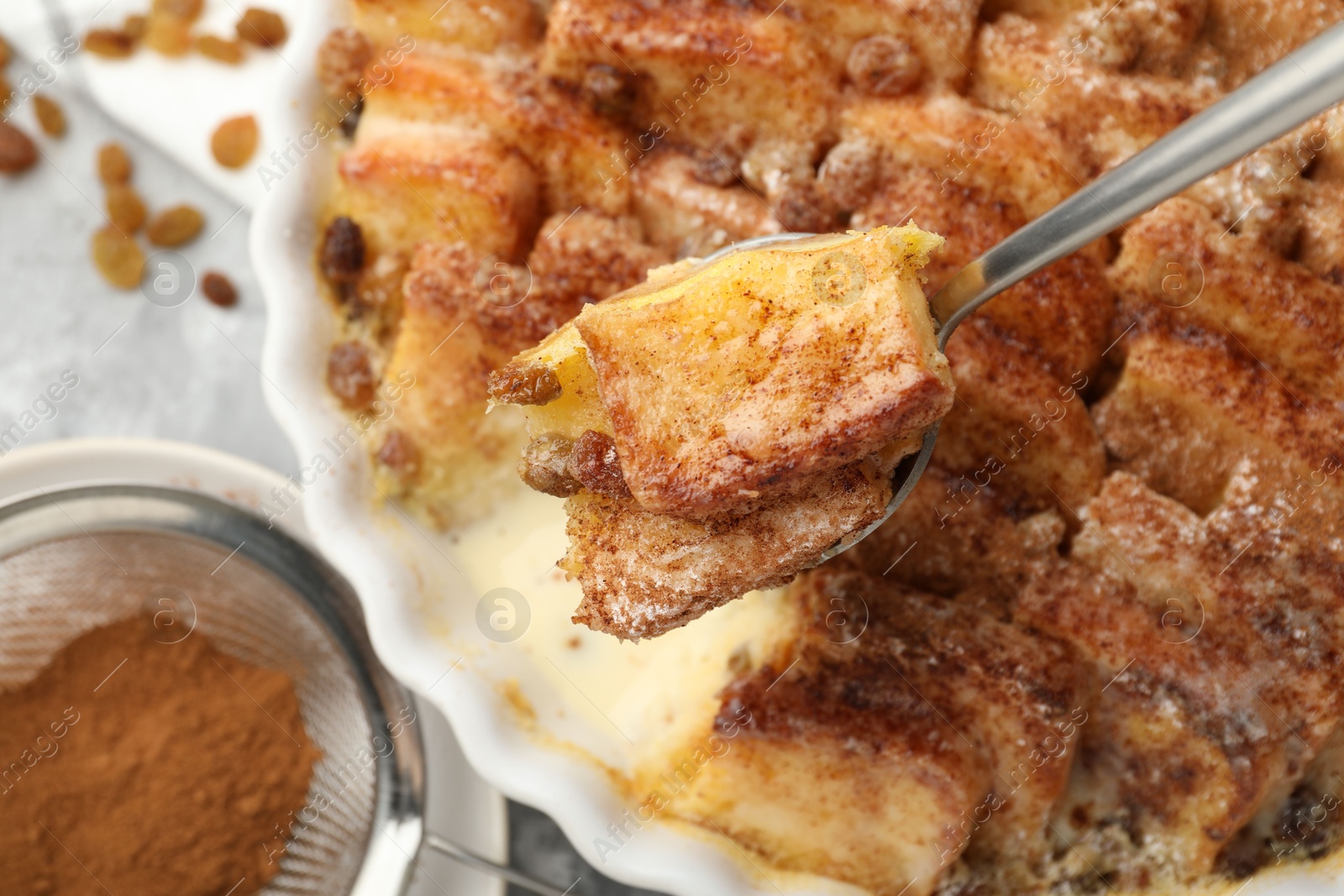 Photo of Eating delicious bread pudding with cinnamon at table, closeup