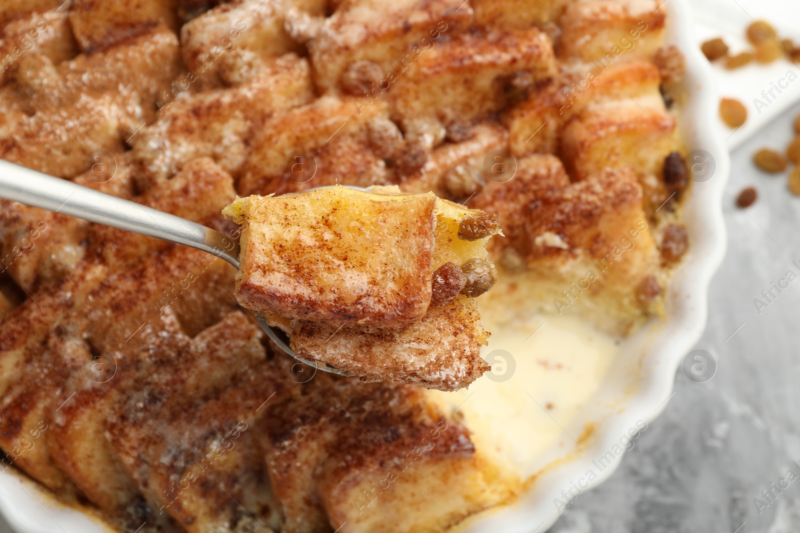 Photo of Eating delicious bread pudding with cinnamon at table, closeup