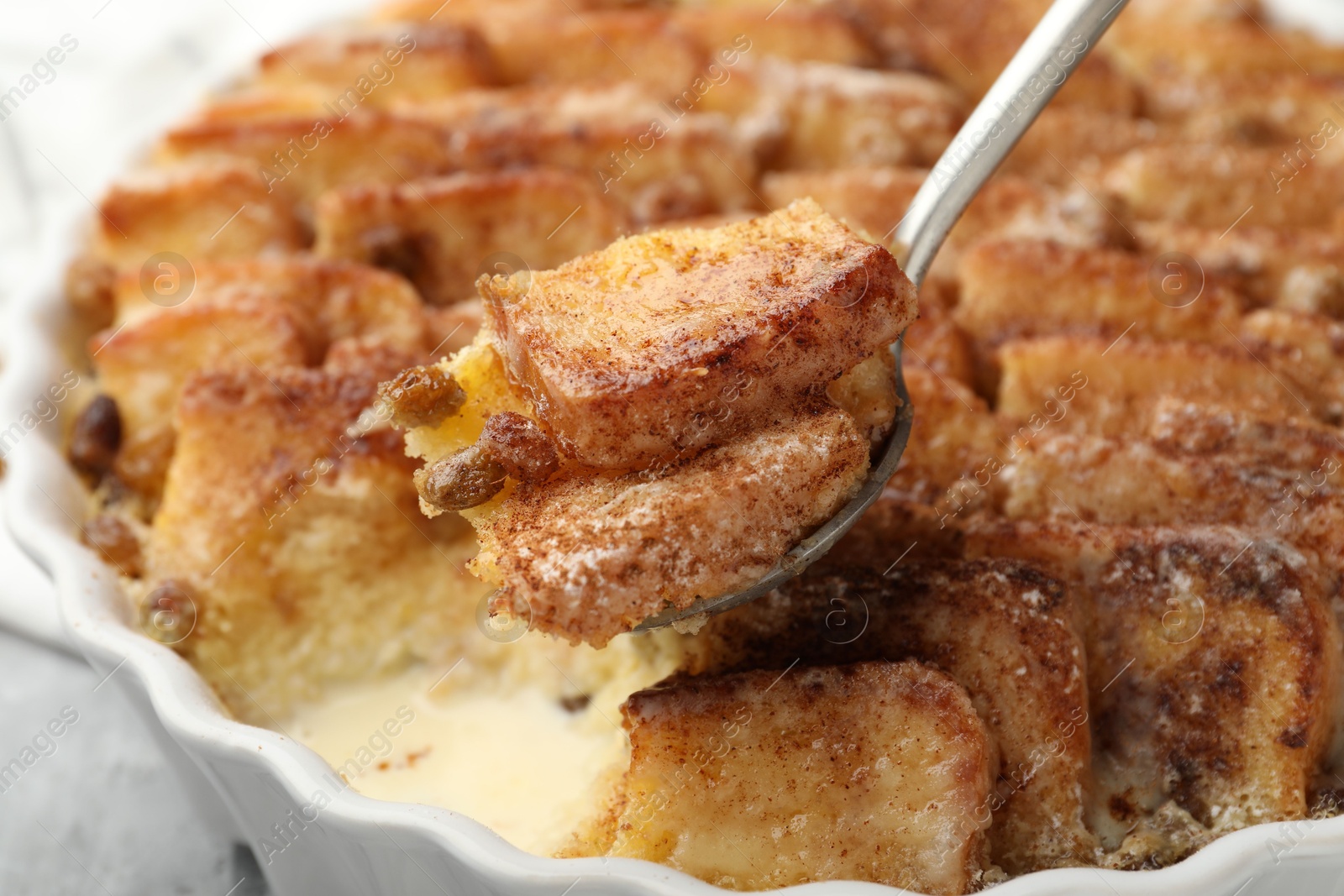 Photo of Eating delicious bread pudding with cinnamon at table, closeup