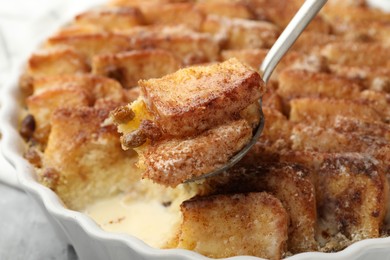 Photo of Eating delicious bread pudding with cinnamon at table, closeup