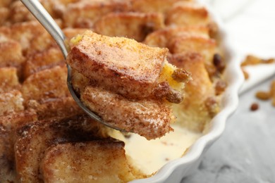 Photo of Eating delicious bread pudding with cinnamon at table, closeup