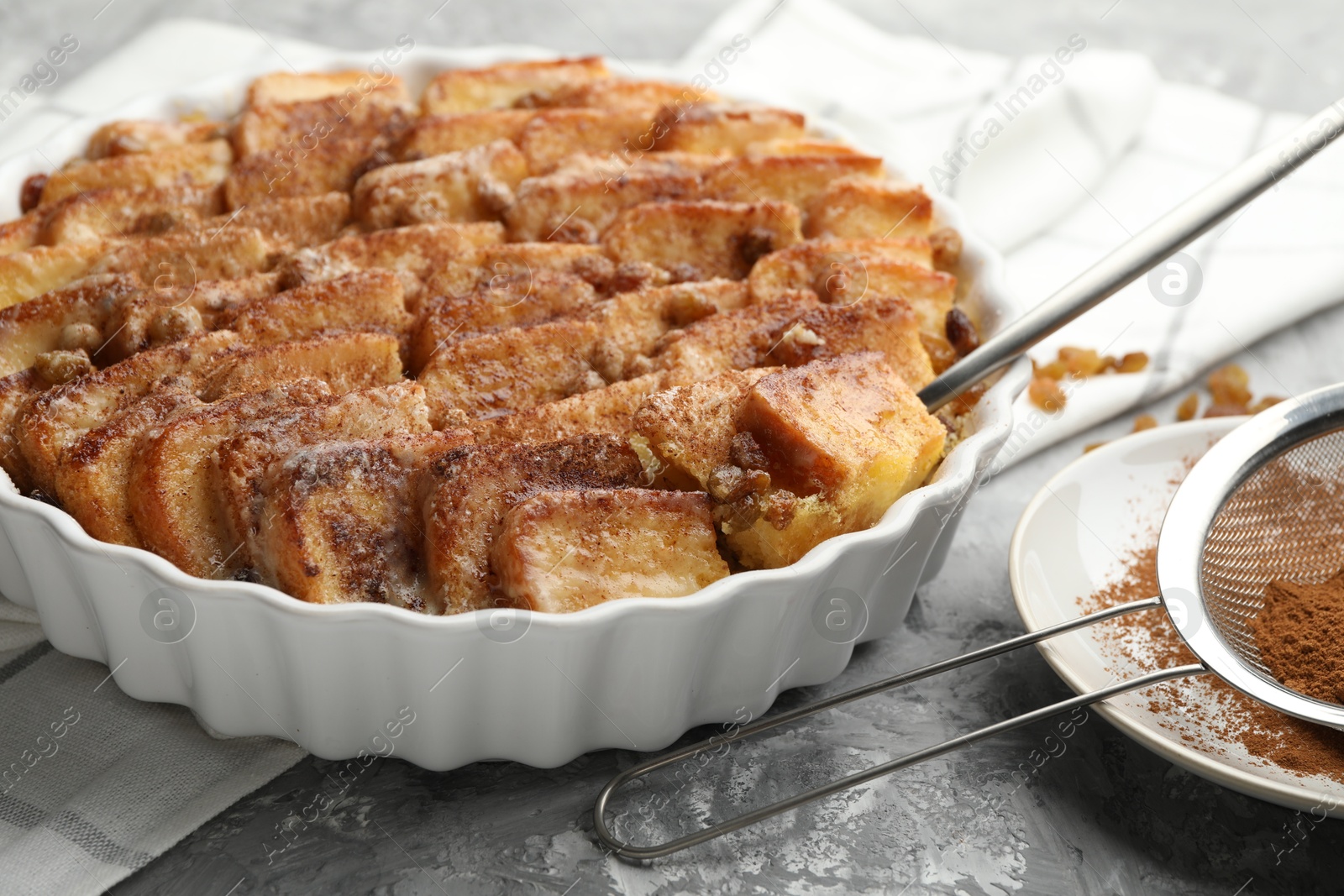 Photo of Delicious bread pudding with raisins and cinnamon on grey table, closeup