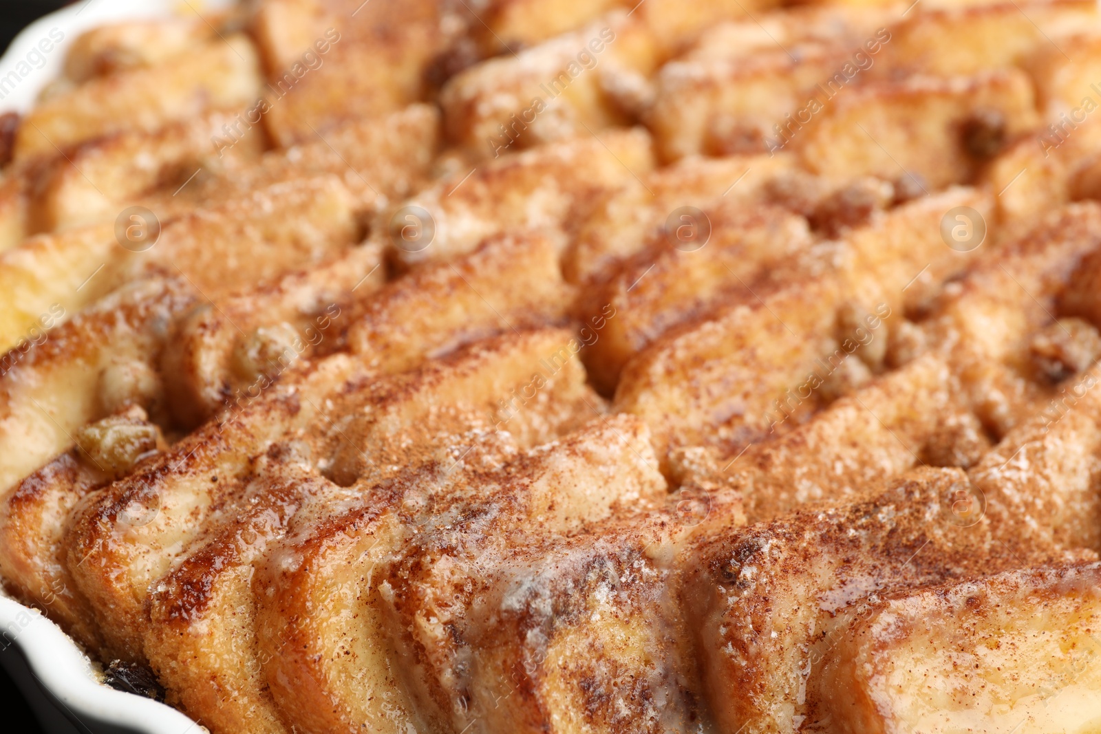 Photo of Delicious bread pudding with raisins and cinnamon in dish, closeup