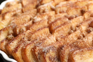 Photo of Delicious bread pudding with raisins and cinnamon in dish, closeup