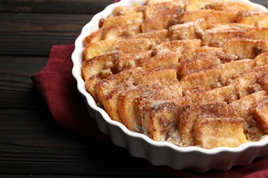 Photo of Delicious bread pudding with raisins and cinnamon on wooden table, closeup