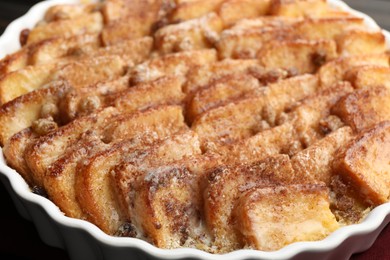 Photo of Delicious bread pudding with raisins and cinnamon in dish, closeup