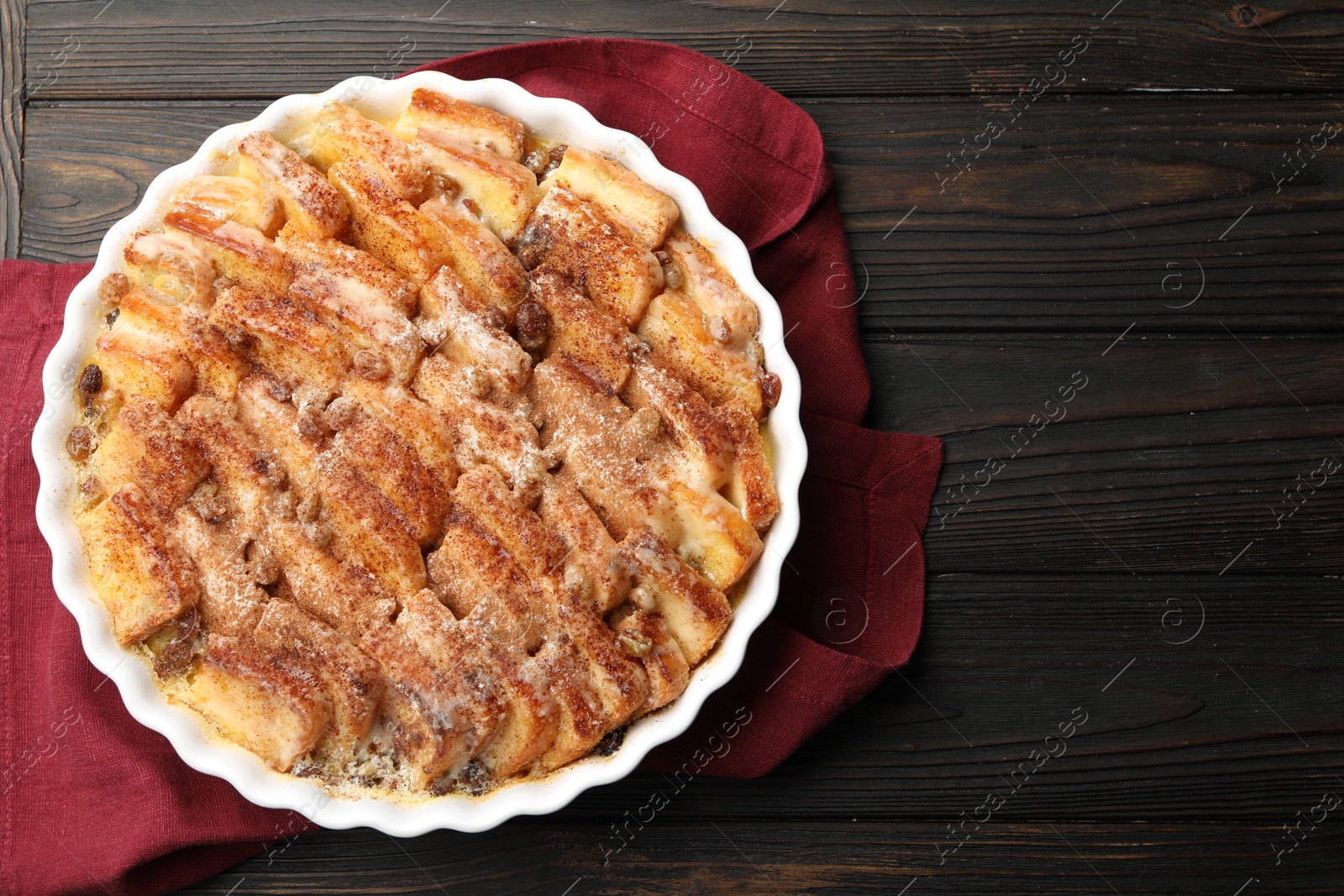 Photo of Delicious bread pudding with raisins and cinnamon on wooden table, top view. Space for text