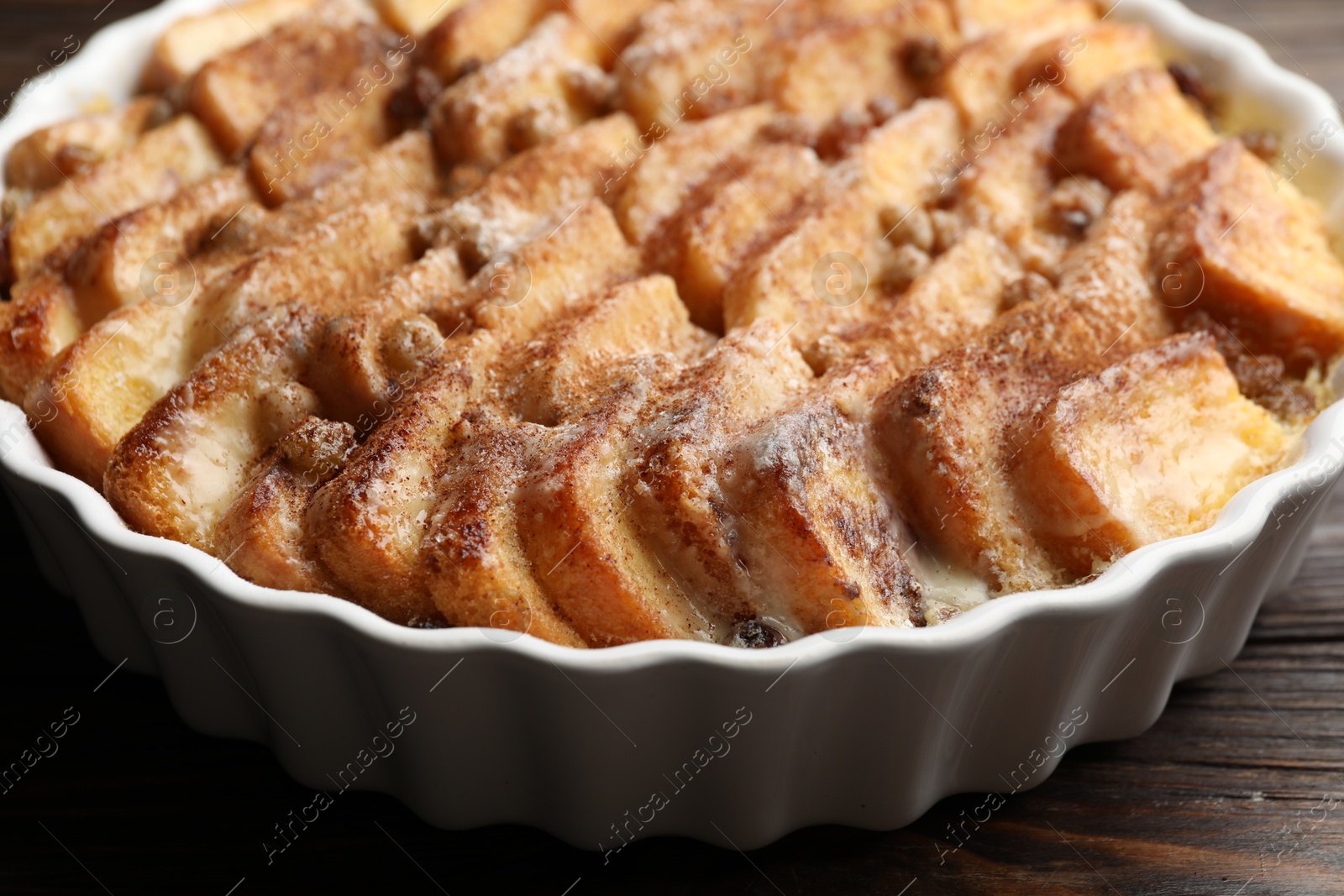 Photo of Delicious bread pudding with raisins and cinnamon on wooden table, closeup