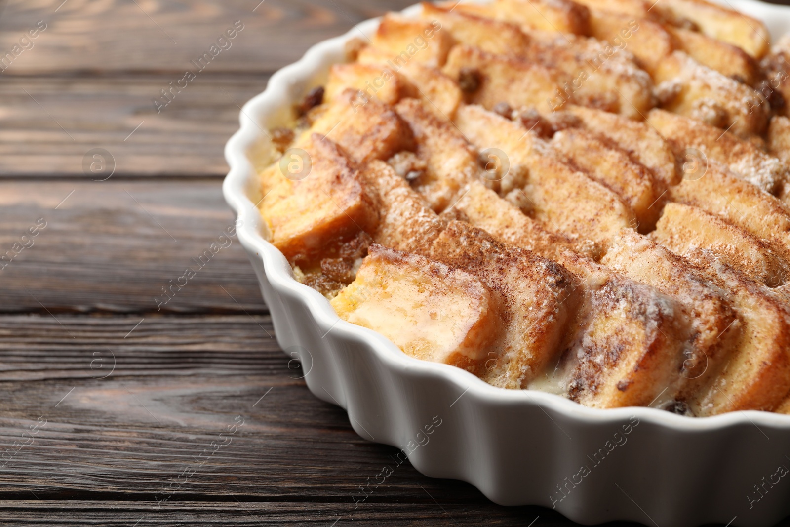 Photo of Delicious bread pudding with raisins and cinnamon on wooden table, closeup