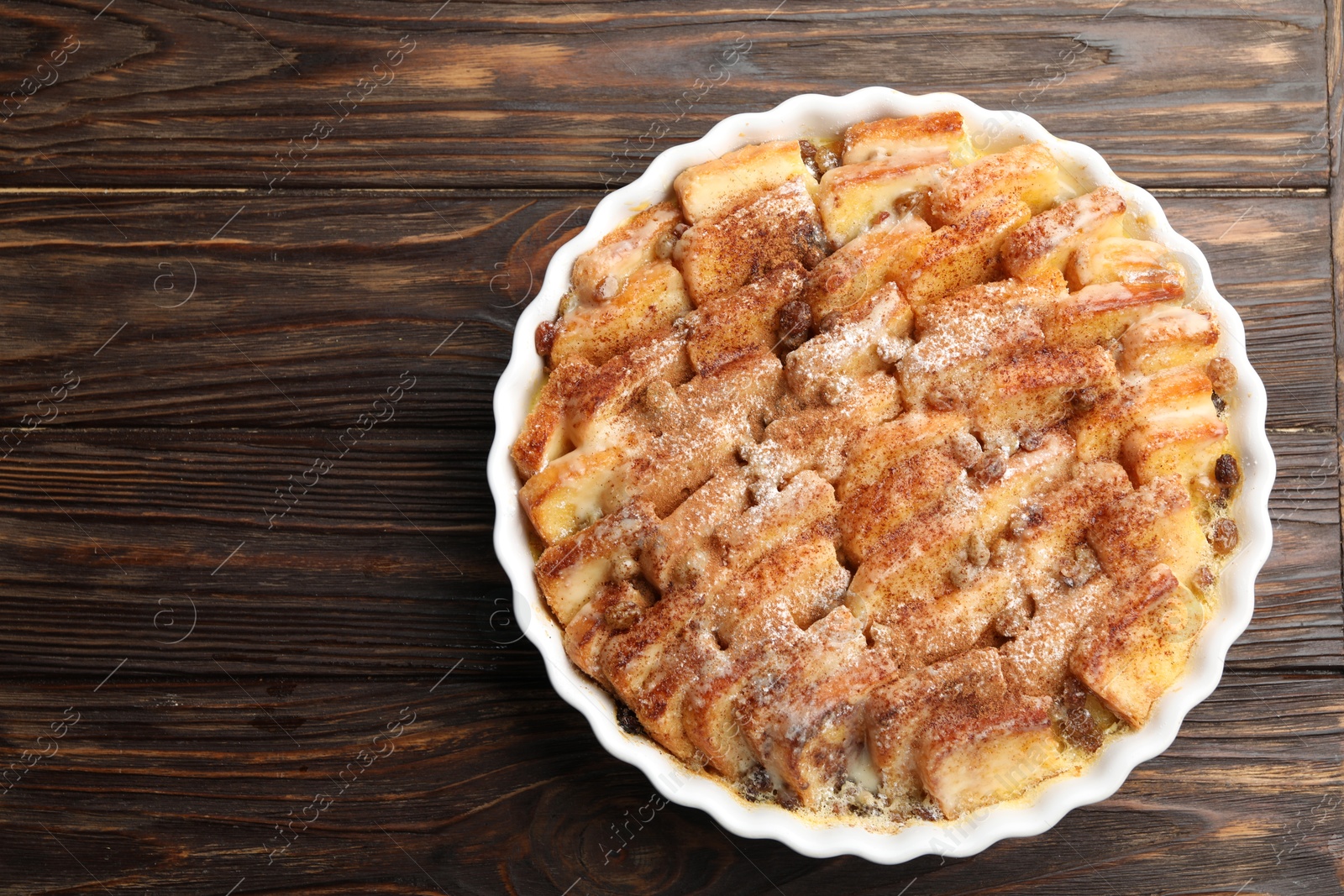 Photo of Delicious bread pudding with raisins and cinnamon on wooden table, top view. Space for text