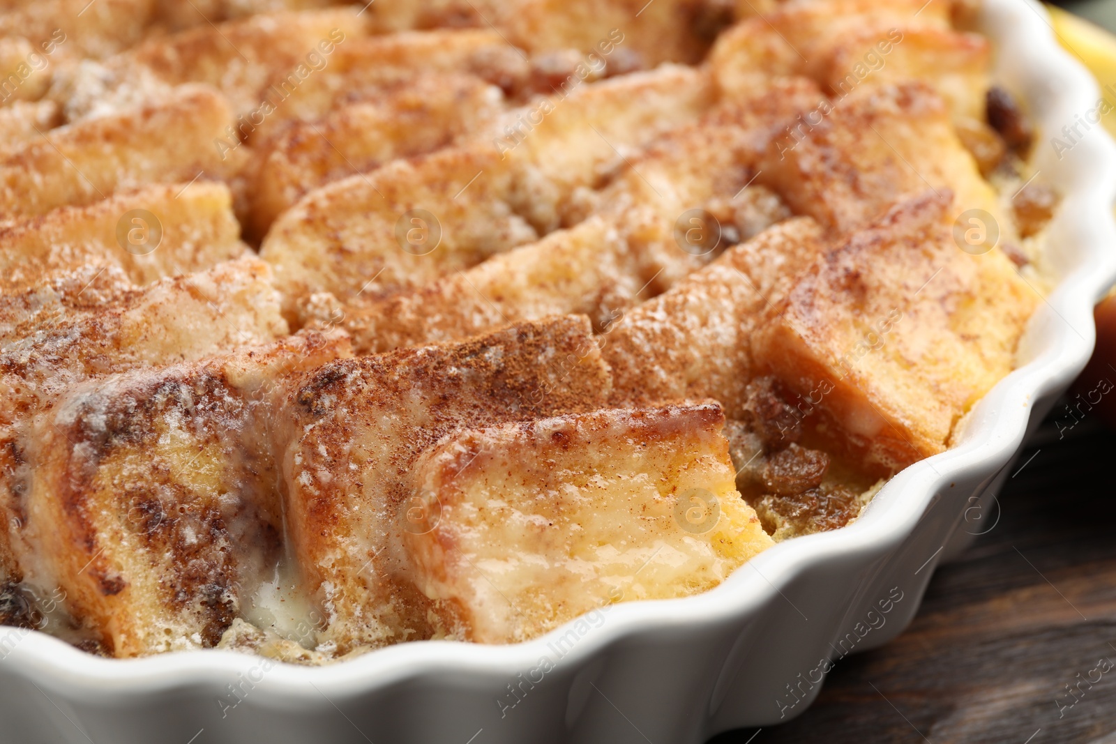 Photo of Delicious bread pudding with raisins and cinnamon on wooden table, closeup