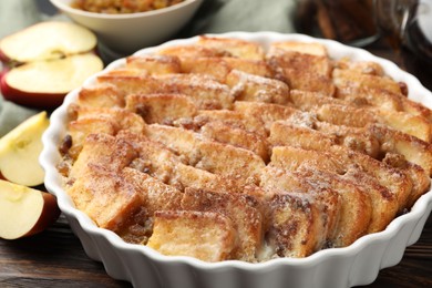 Photo of Delicious bread pudding with raisins, cinnamon and apples on wooden table, closeup