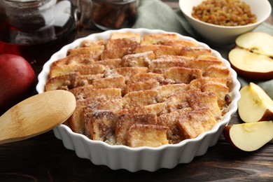 Photo of Delicious bread pudding with raisins, cinnamon and apples on wooden table, closeup