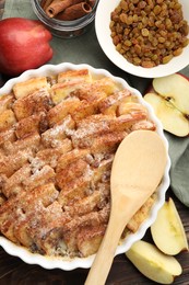 Photo of Delicious bread pudding with raisins, cinnamon and apples on wooden table, flat lay