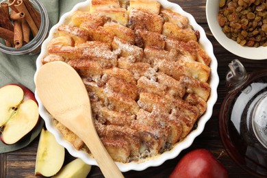 Photo of Delicious bread pudding with raisins, cinnamon and apples on wooden table, flat lay