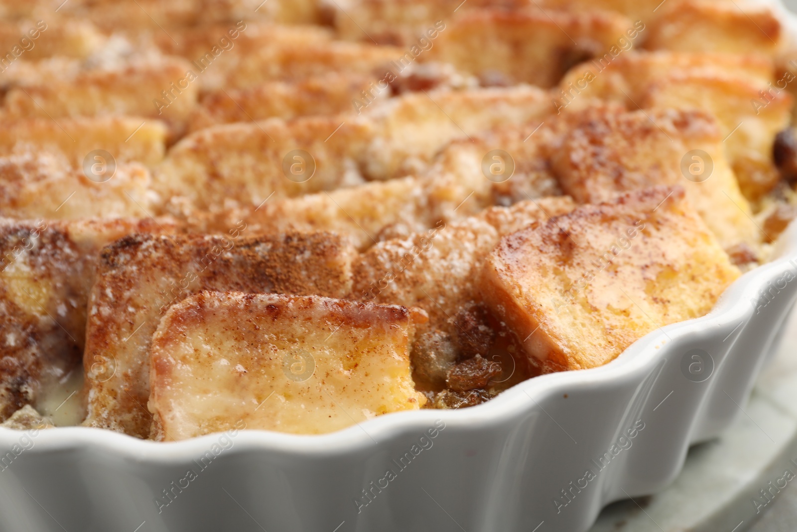 Photo of Delicious bread pudding with raisins and cinnamon in dish, closeup