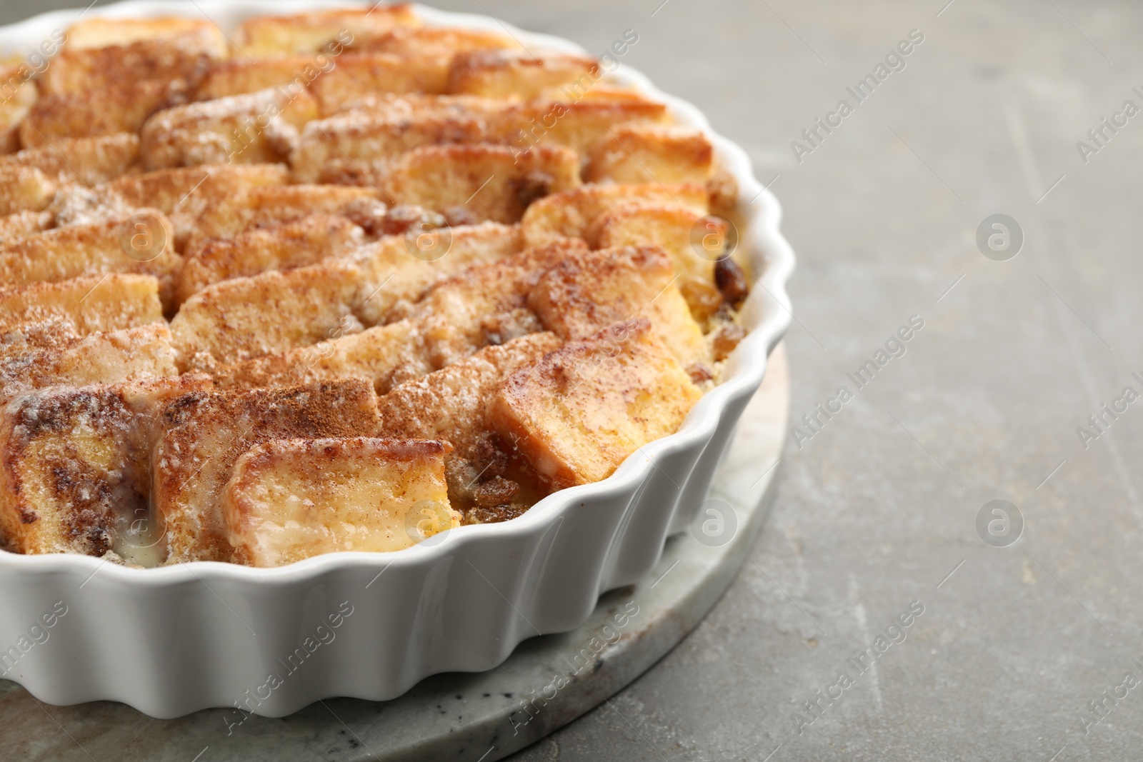 Photo of Delicious bread pudding with raisins and cinnamon on grey table, closeup