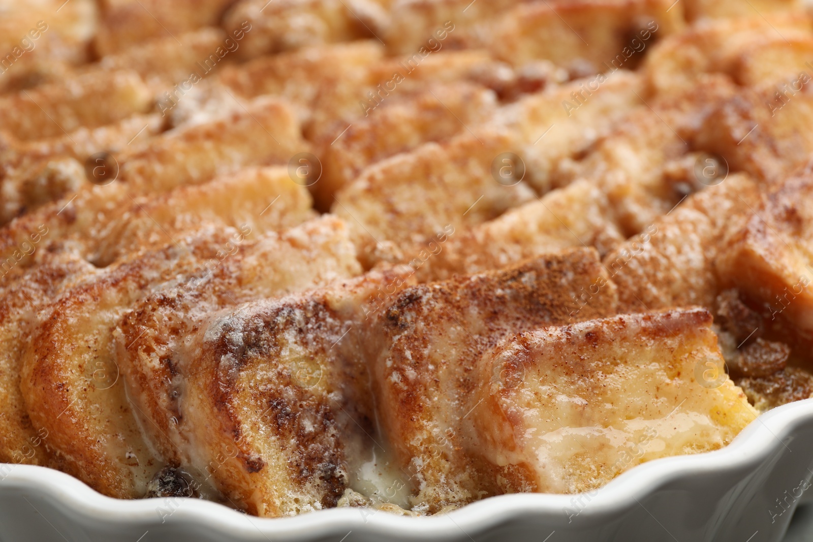 Photo of Delicious bread pudding with raisins and cinnamon in dish, closeup