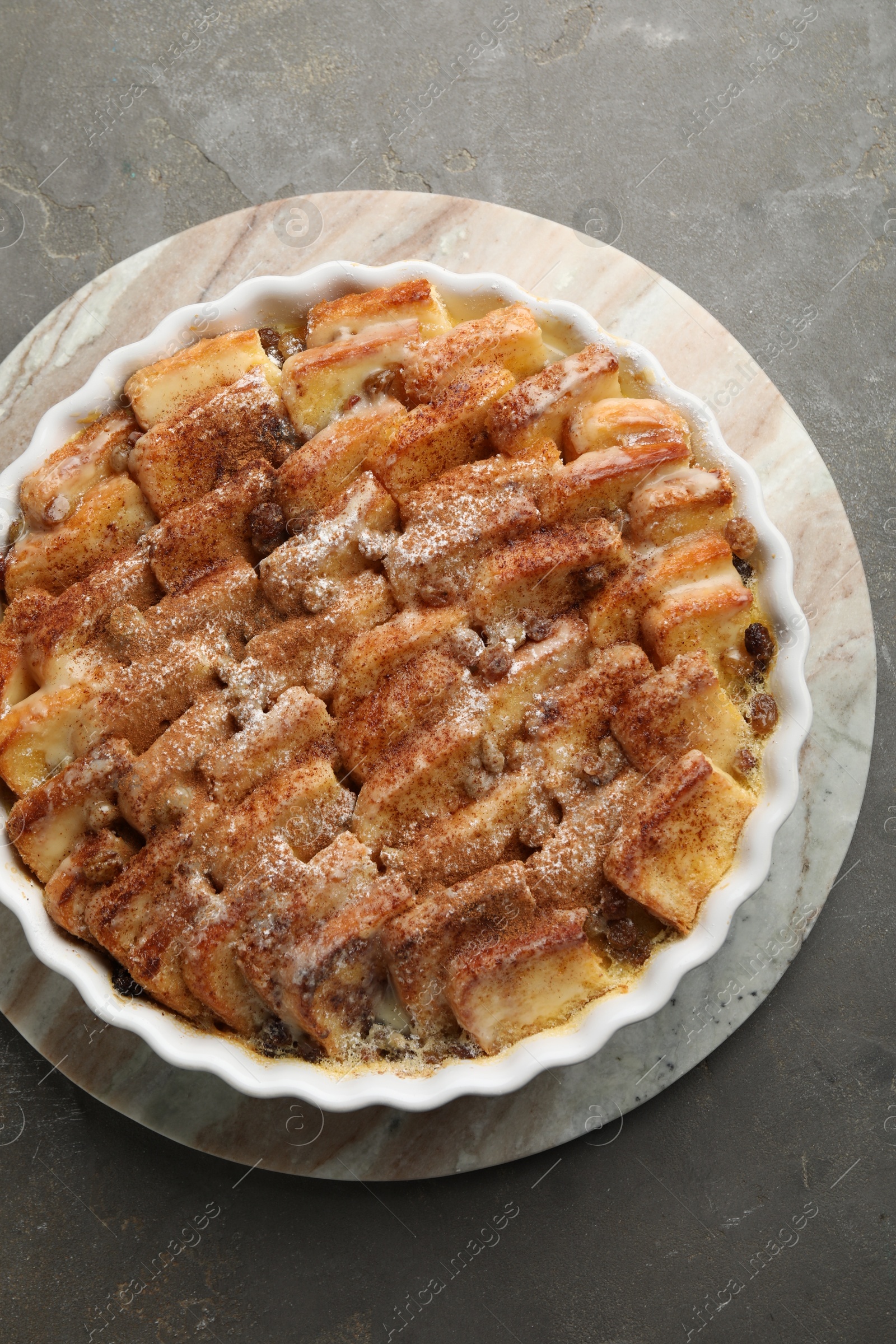 Photo of Delicious bread pudding with raisins and cinnamon on grey table, top view