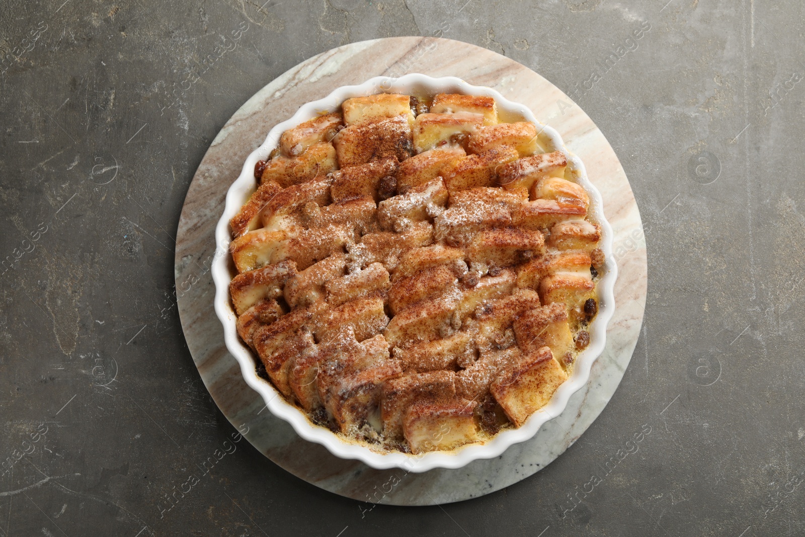 Photo of Delicious bread pudding with raisins and cinnamon on grey table, top view