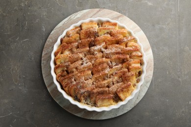 Photo of Delicious bread pudding with raisins and cinnamon on grey table, top view