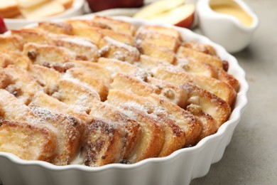 Photo of Delicious bread pudding with raisins and powdered sugar on grey table, closeup