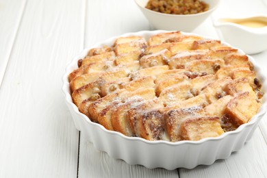 Photo of Delicious bread pudding with raisins and powdered sugar on white wooden table, closeup. Space for text