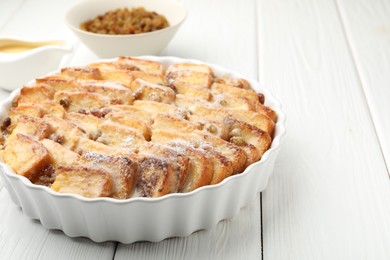 Photo of Delicious bread pudding with raisins and powdered sugar on white wooden table, closeup. Space for text