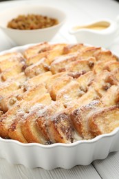 Photo of Delicious bread pudding with raisins and powdered sugar on white wooden table, closeup