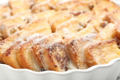 Photo of Delicious bread pudding with raisins and powdered sugar in dish, closeup