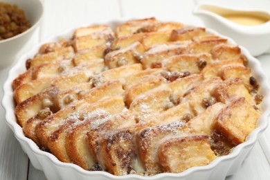 Photo of Delicious bread pudding with raisins and powdered sugar on white wooden table, closeup