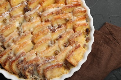 Photo of Delicious bread pudding with raisins and powdered sugar on black table, top view