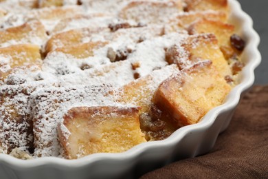 Photo of Delicious bread pudding with raisins and powdered sugar on table, closeup