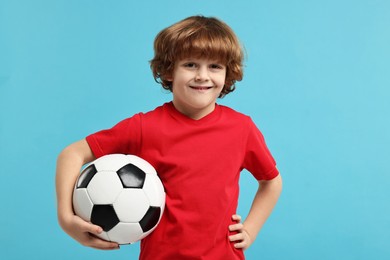 Photo of Little boy with soccer ball on light blue background