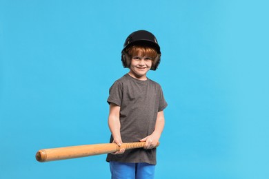 Photo of Little boy in helmet with baseball bat on light blue background