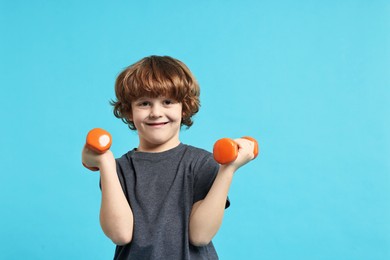 Photo of Little boy with dumbbells on light blue background