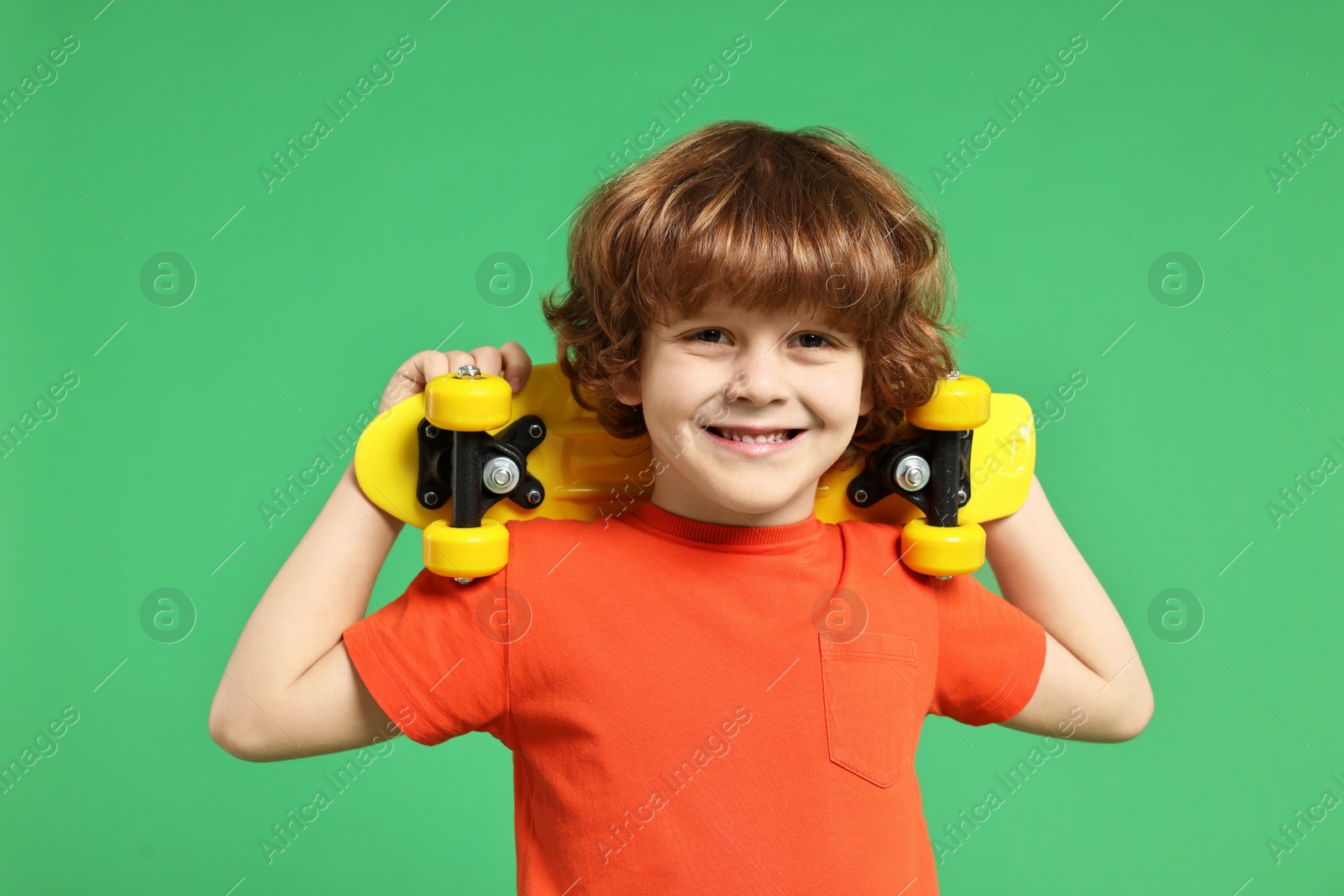 Photo of Little boy with penny board on light green background