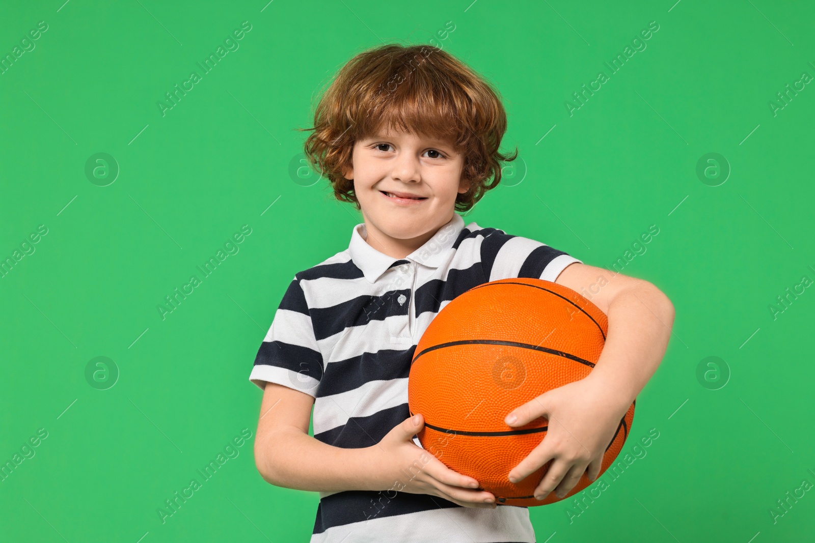 Photo of Little boy with basketball ball on light green background