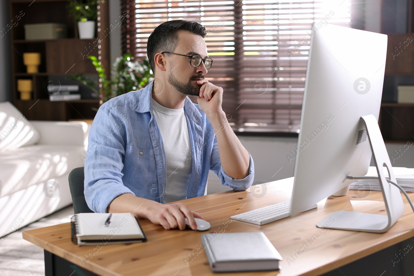 Photo of Handsome man working with computer at desk indoors. Home office