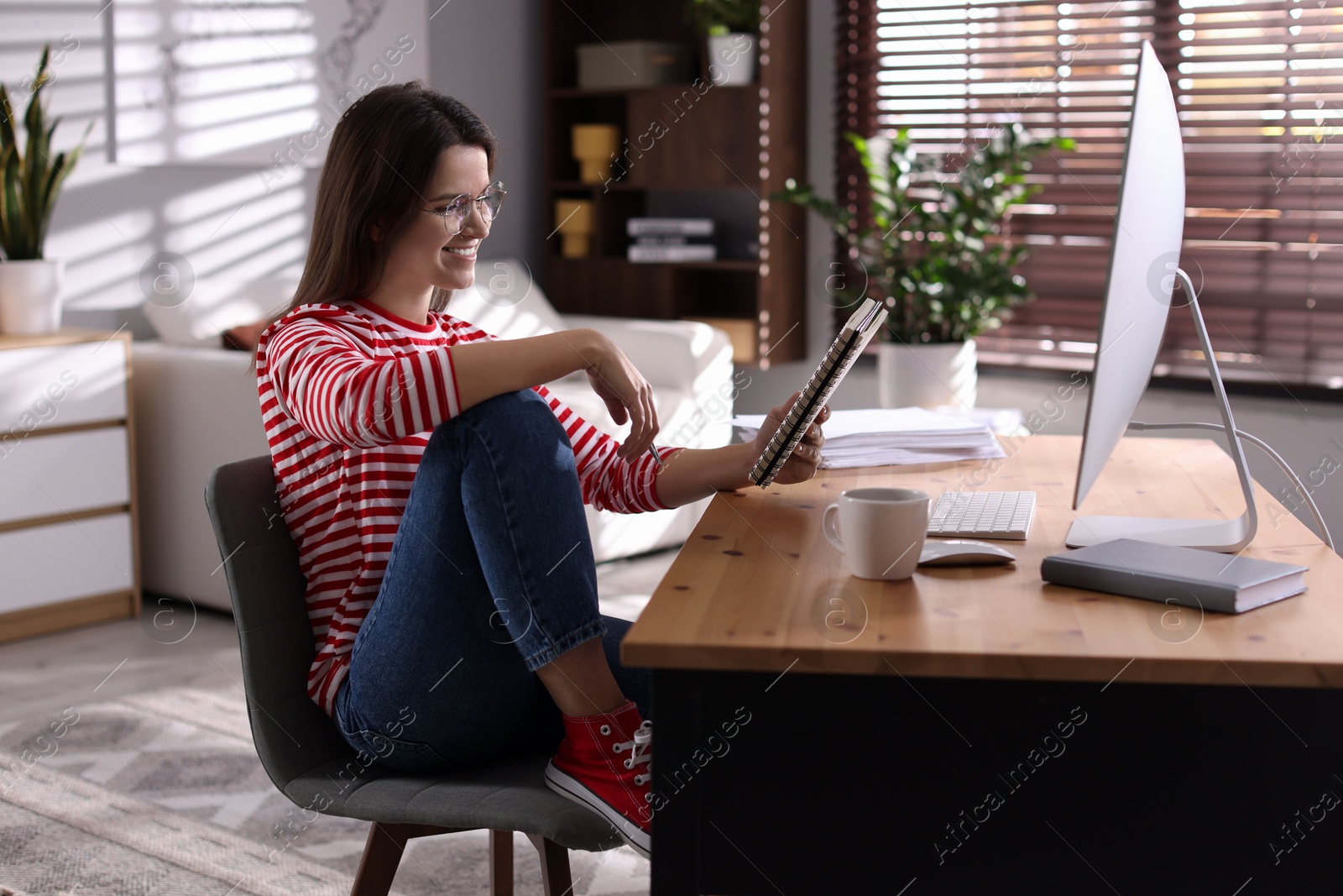 Photo of Happy woman working at desk with computer indoors. Home office