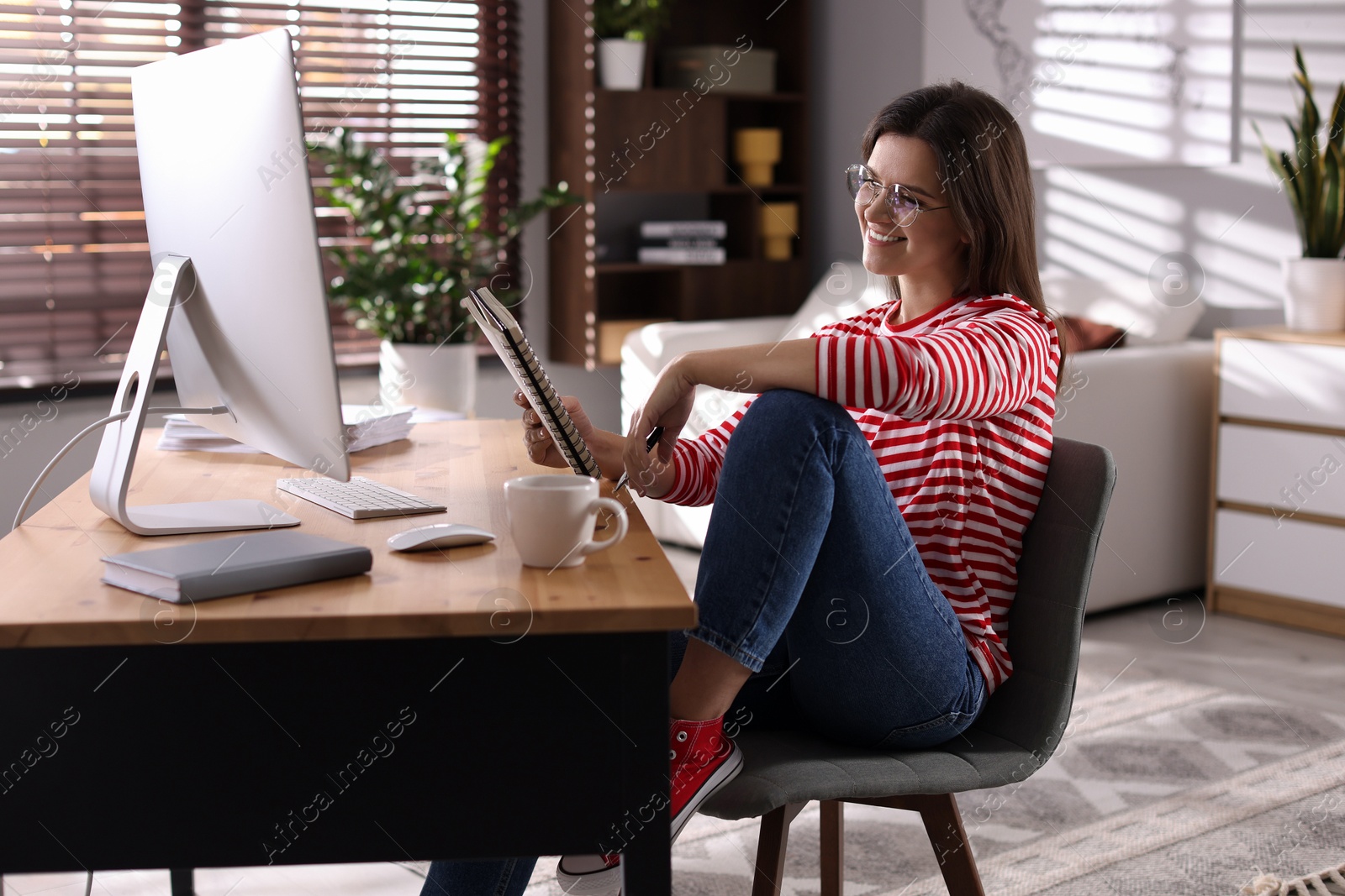 Photo of Happy woman working at desk with computer indoors. Home office