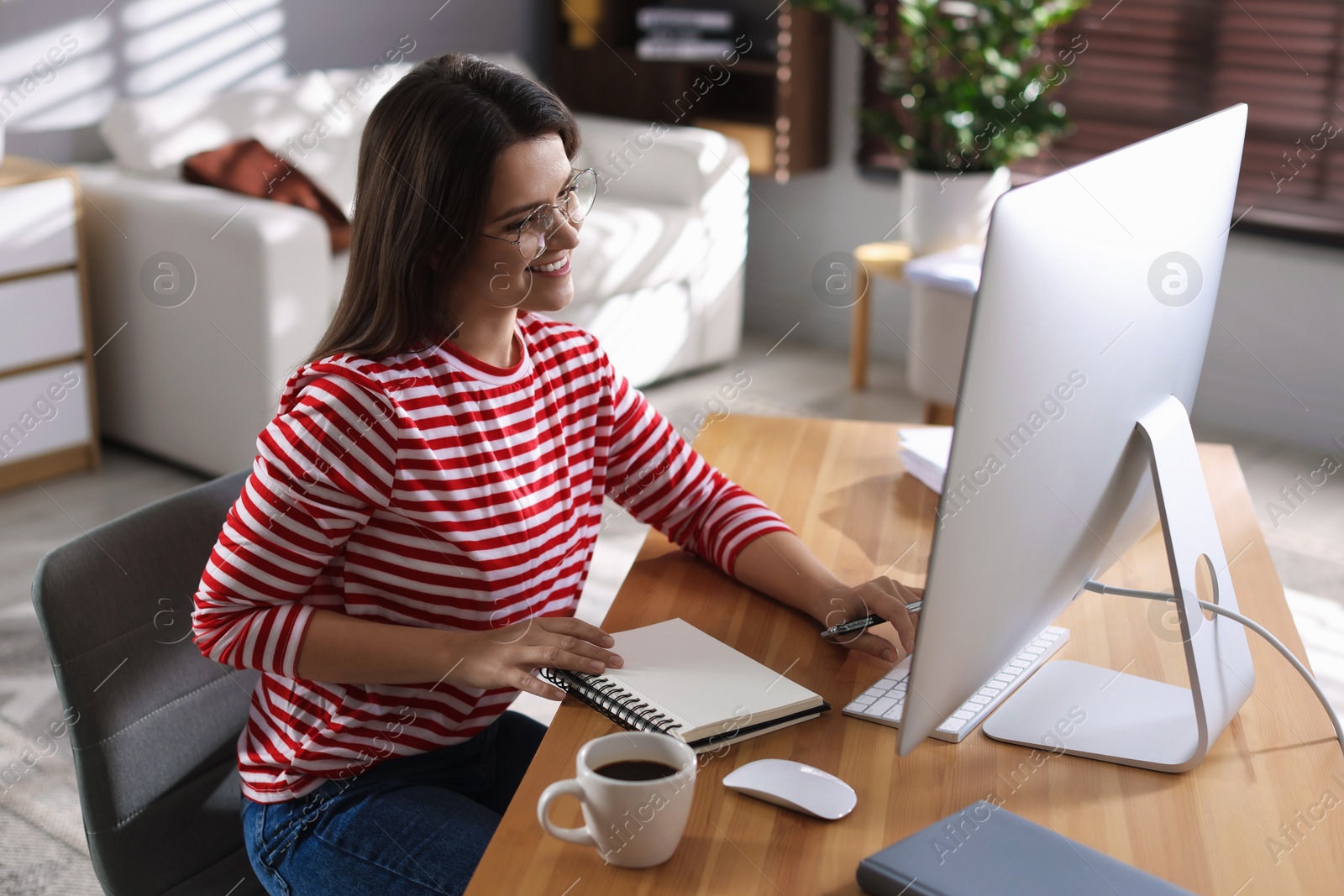 Photo of Happy woman working with computer at desk indoors. Home office