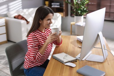 Photo of Happy woman working with computer at desk indoors. Home office